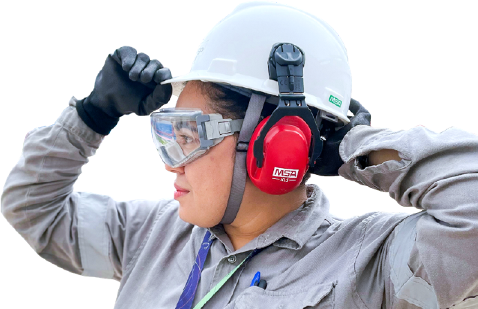 On the right, an Ultra Group employee with her hands on her protective helmet, wearing personal protective equipment.